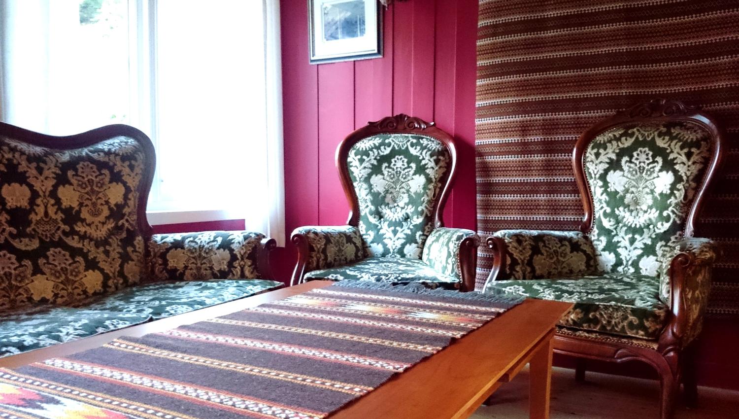 Hyggjeleg sittegruppe med antikke stolar og sofa i tradisjonell stil på Ullensvang Gjesteheim.