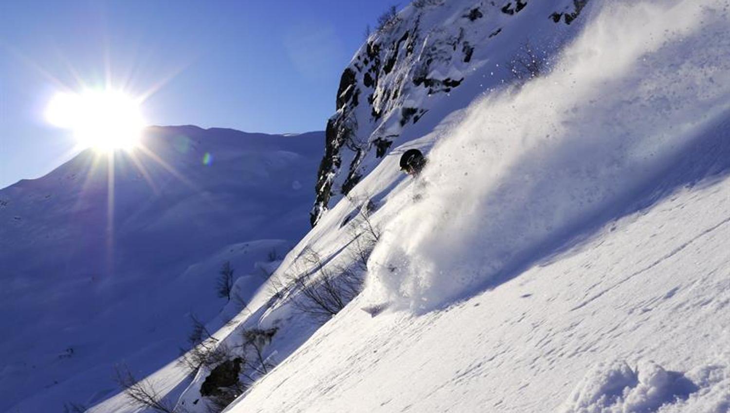 Freerider carving through deep powder snow in the sunset at Røldal Ski Resort.