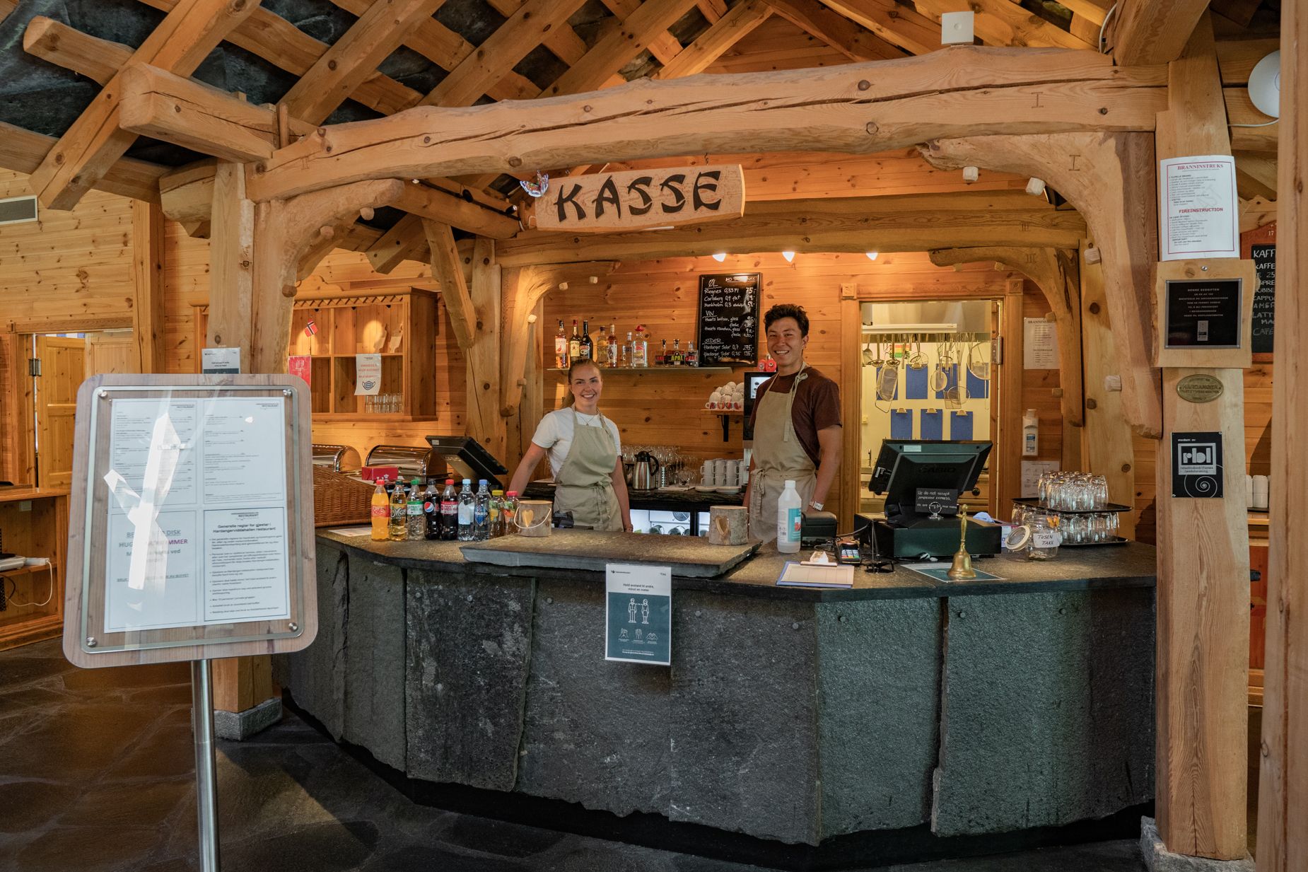 To servitører som står bak kassa.