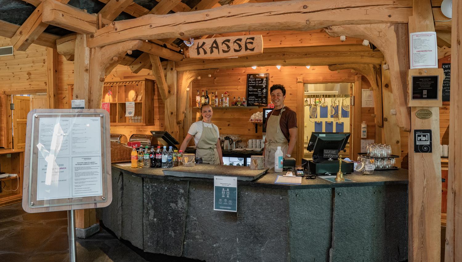 To servitører som står bak kassa.