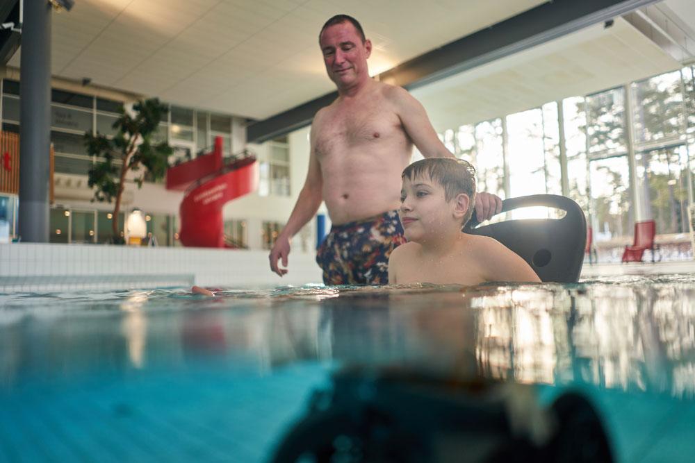 far og sønn i rullestol i badebasseng i Skien fritidspark