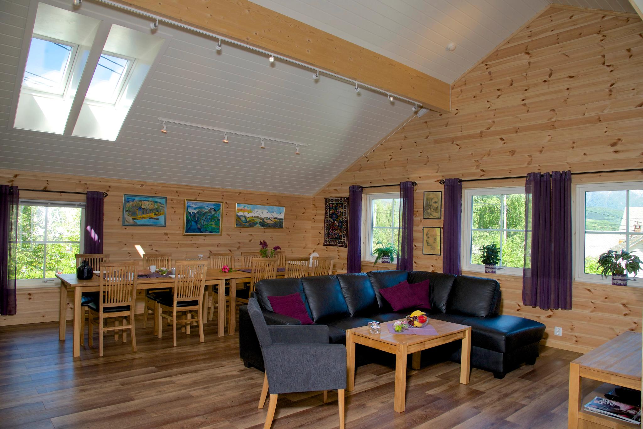 Lys og romsleg stove med stort spisebord, moderne sofagruppe og store vindauge hjå Vågen Rom og Hytteutleige i Hardanger.