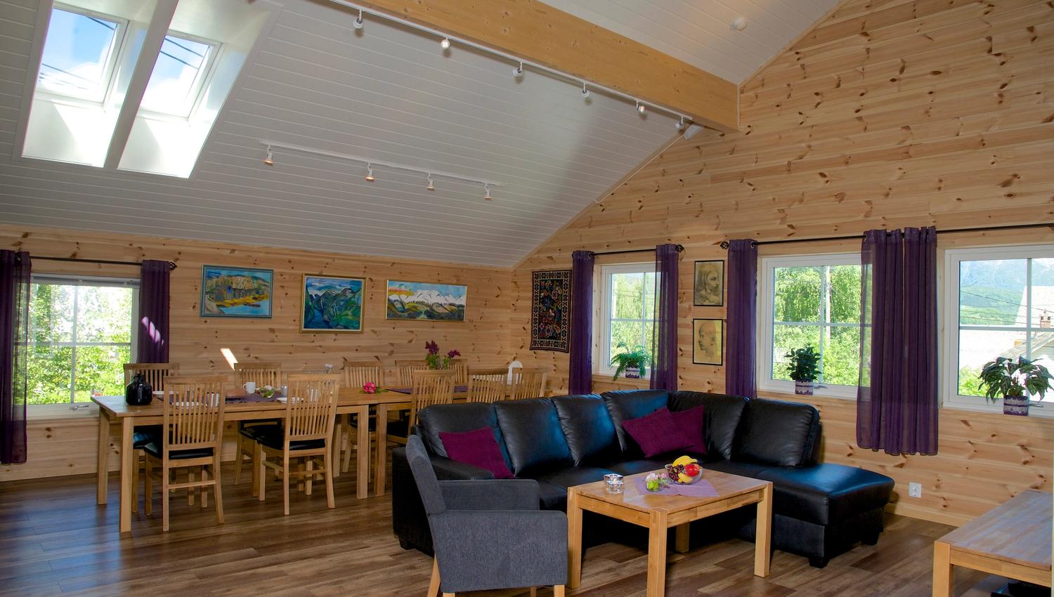 Lys og romsleg stove med stort spisebord, moderne sofagruppe og store vindauge hjå Vågen Rom og Hytteutleige i Hardanger.