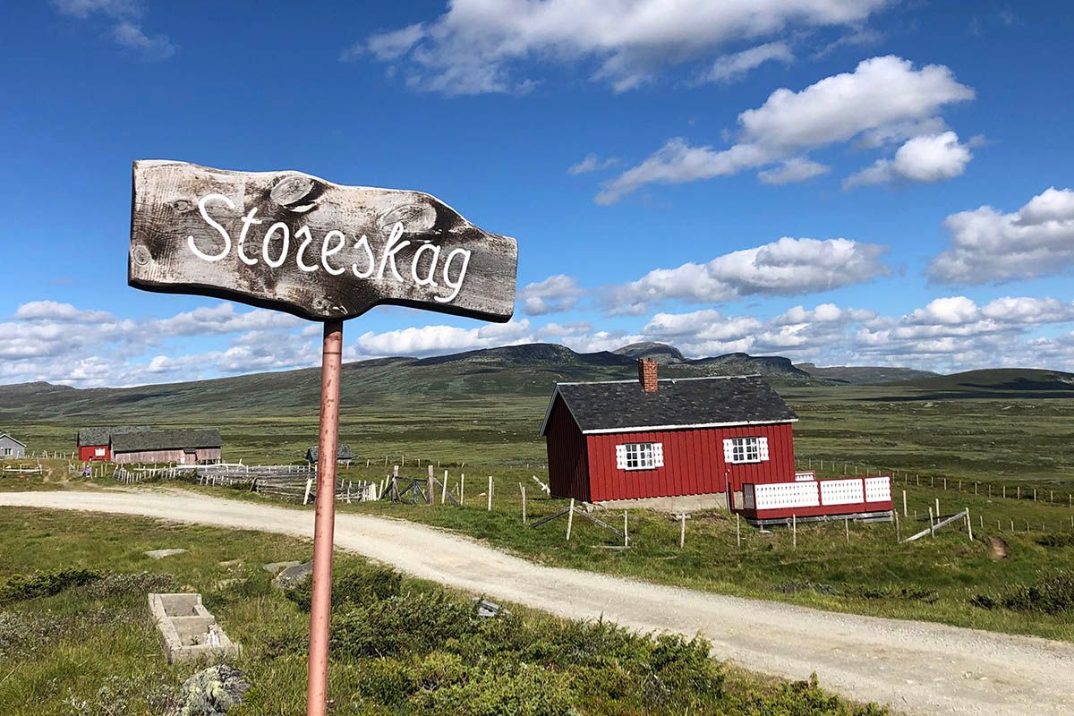 Red summer farm hut and a wooden sign at Storeskag