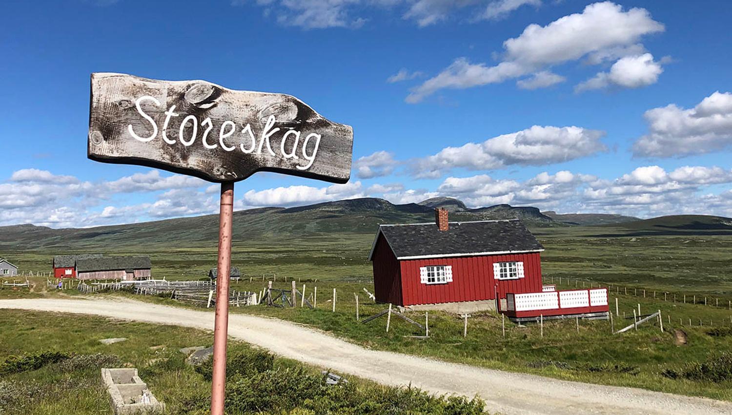 Red summer farm hut and a wooden sign at Storeskag