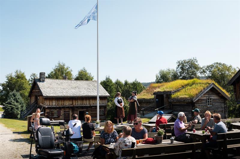 People are sitting in fornt of the serving hut at Geilojordet and watch theatre. 