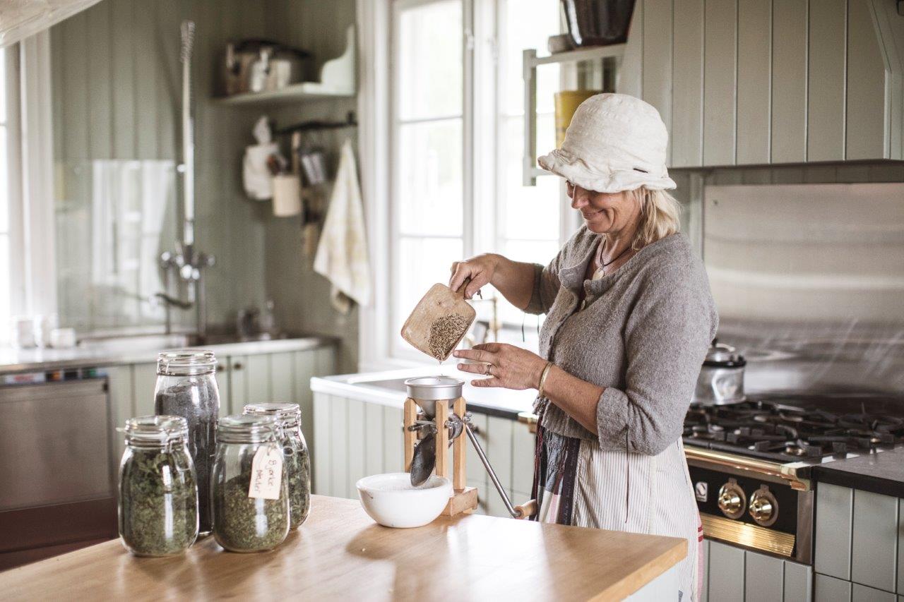 dame i gammeldagse klær på et gammelt  kjøkken som baker