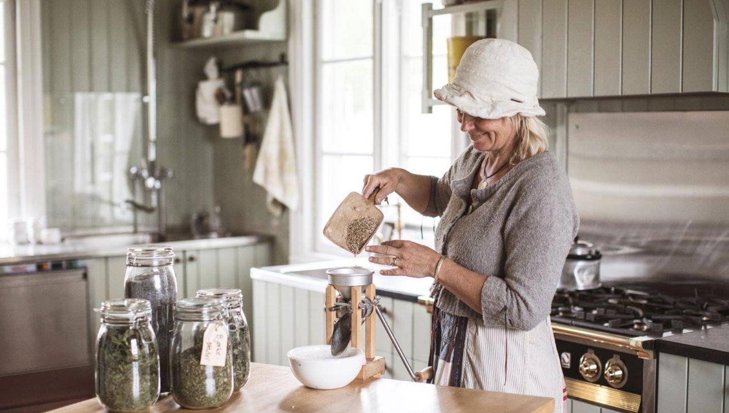 dame i gammeldagse klær på et gammelt kjøkken som baker