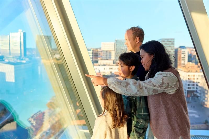 Familie som ser utover byen gjennom et panoramvindu