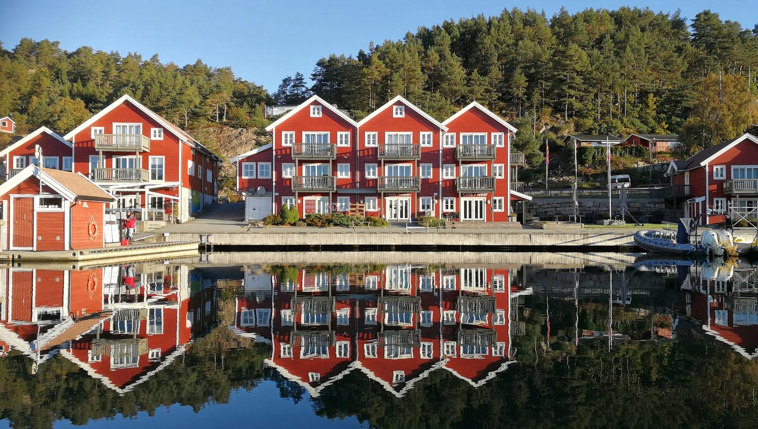 Tregde Ferie, photo taken from the water facing the dock, red buildings with white trim