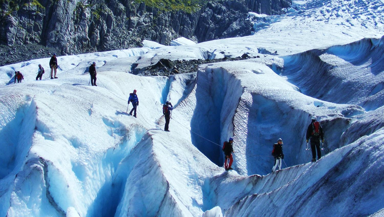 Guidet bretur der deltakarar kryssar sprekker i isen omgitt av ville fjell.