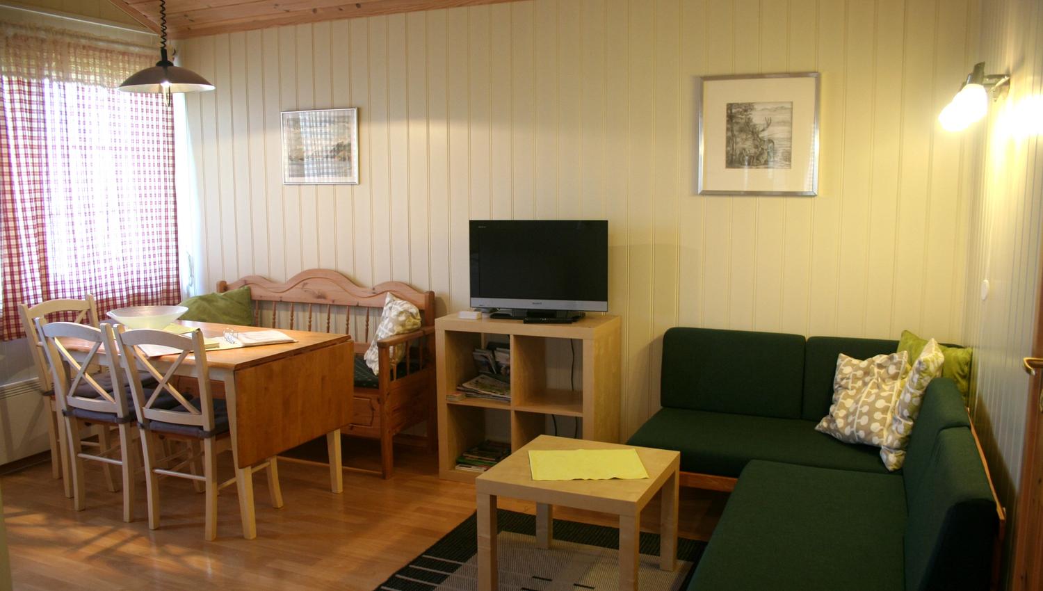 Lys og koseleg stove med spisebord, sofa og TV på Oddland Camping i Hardanger.