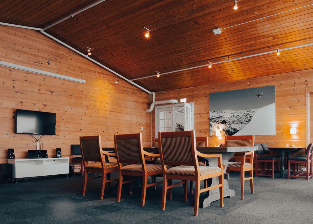 oppholdsrom med bord og stoler og TV på Austbø Hotell