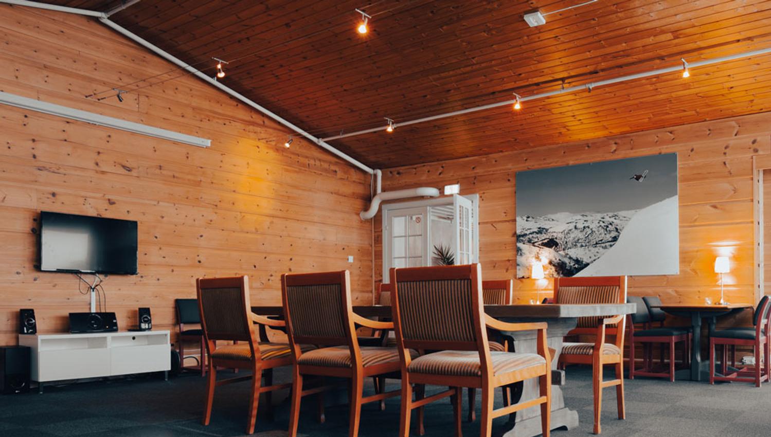 oppholdsrom med bord og stoler og TV på Austbø Hotell