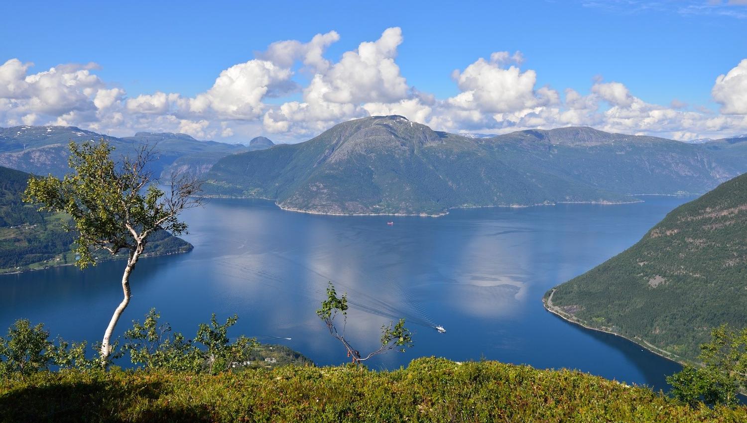 View from Dronningstien over the blue fjord and mountains under a clear sky.