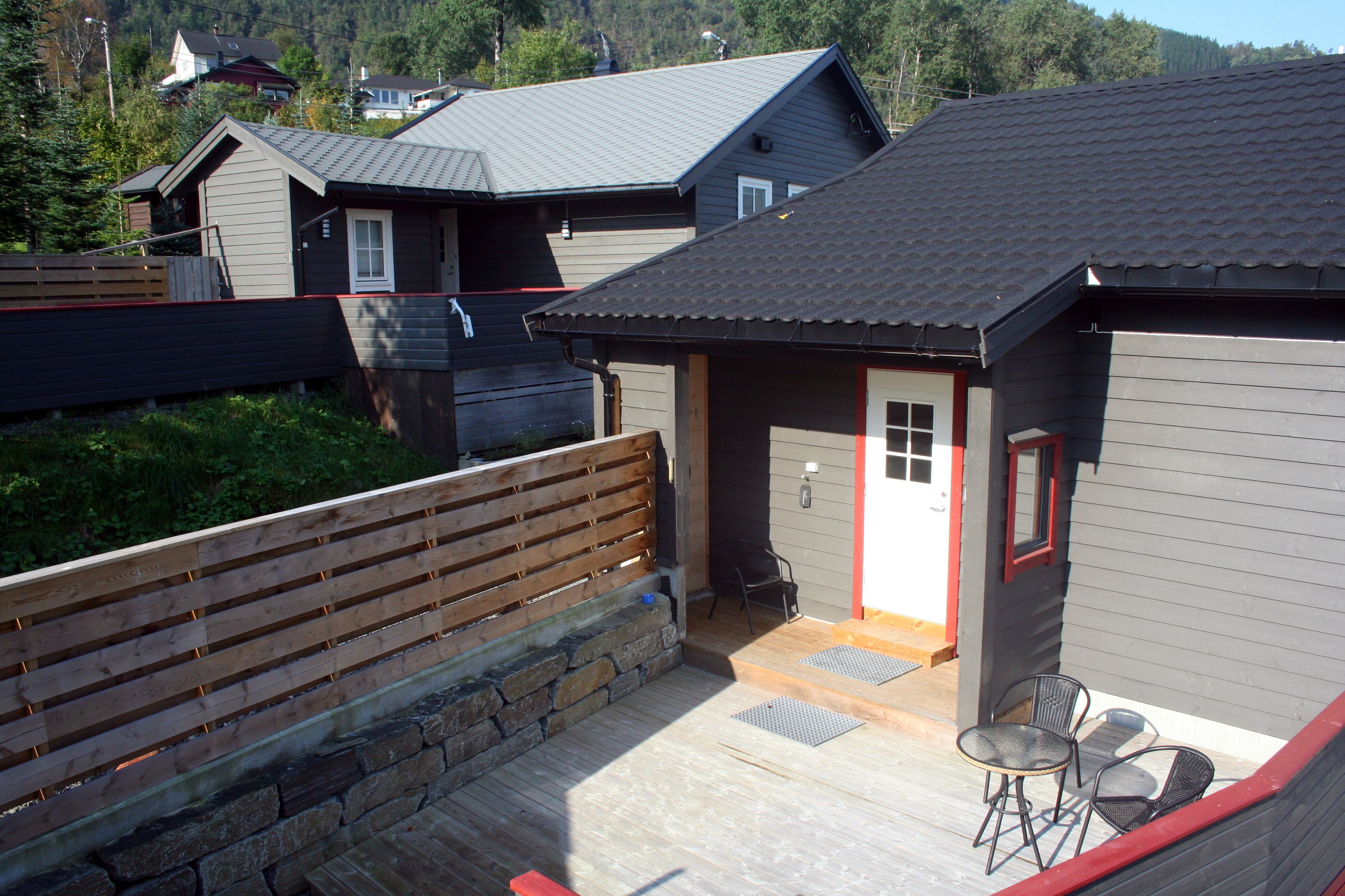 Terrasse og uteområde ved Vågen Rom og Hytteutleige med inngangsdør og utemøblar.