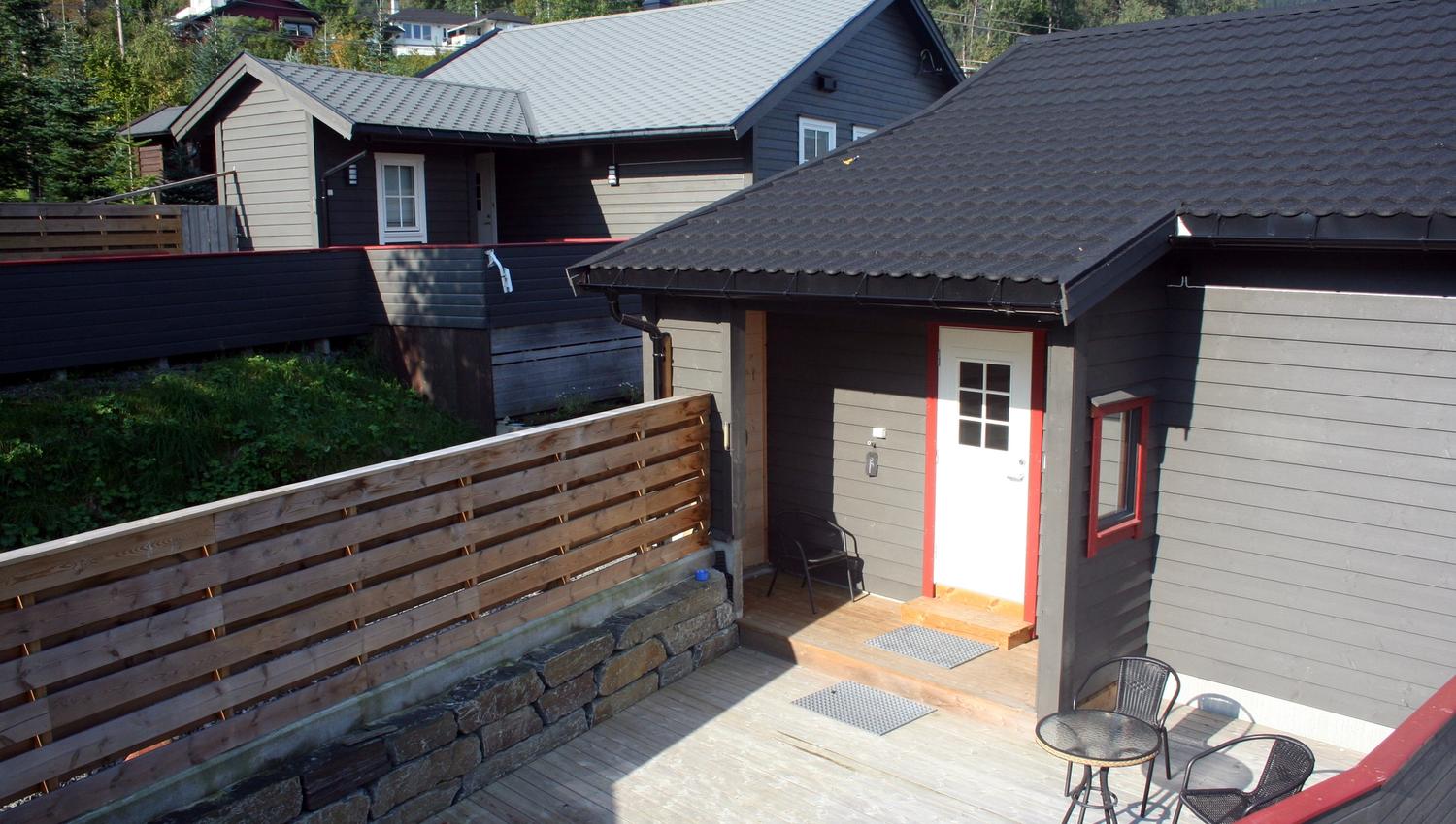Terrasse og uteområde ved Vågen Rom og Hytteutleige med inngangsdør og utemøblar.