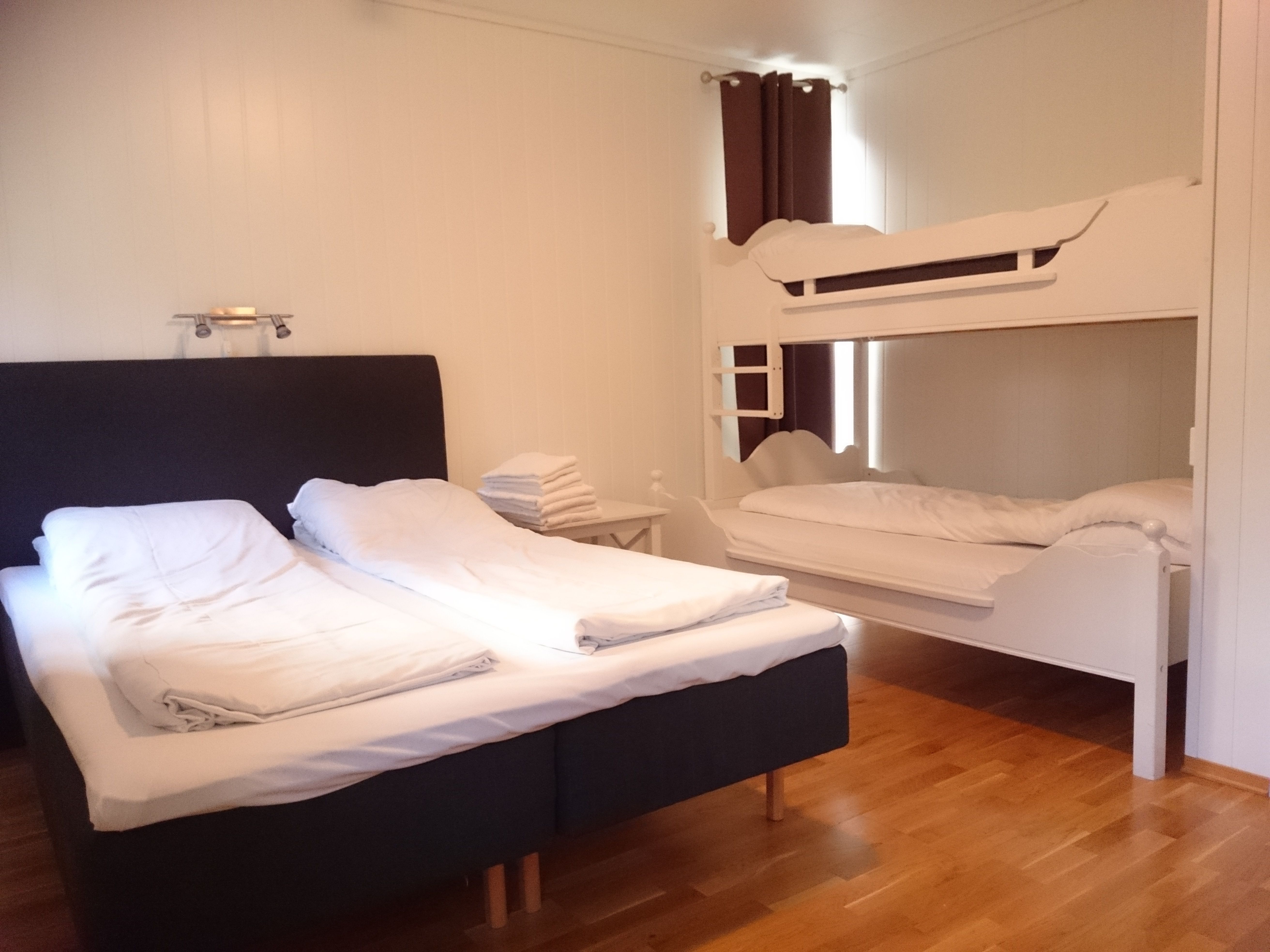 Lyst og moderne soverom på Ullensvang Gjesteheim med dobbeltseng, køyeseng og god plass for familiar.