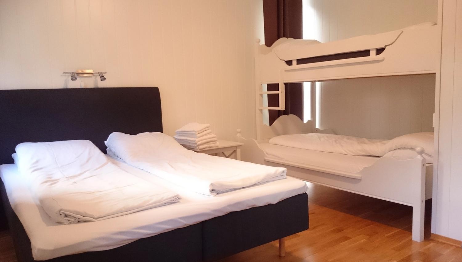 Lyst og moderne soverom på Ullensvang Gjesteheim med dobbeltseng, køyeseng og god plass for familiar.