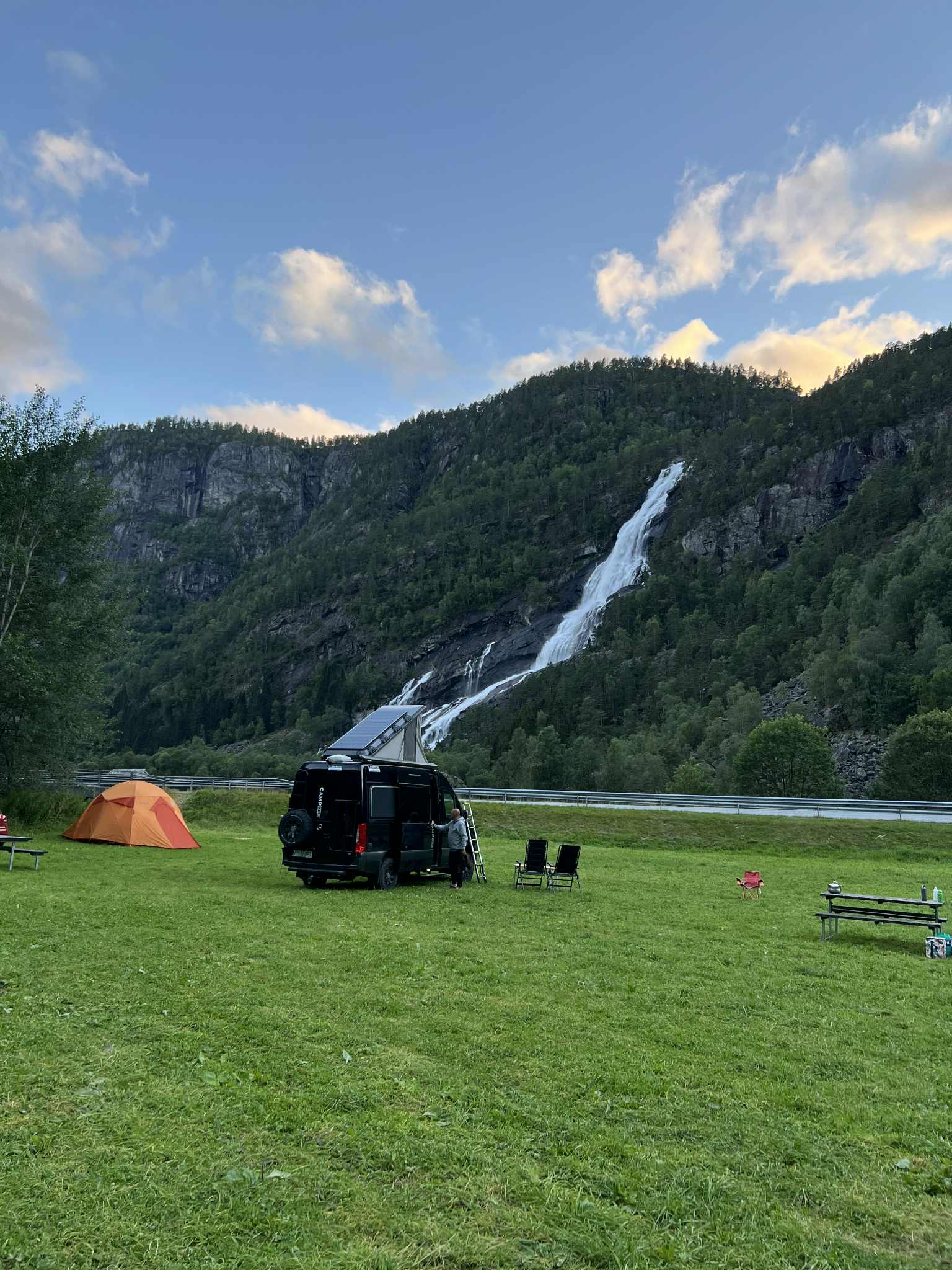 Campingvogn og telt på Hildal Camping med mektig foss i bakgrunnen.