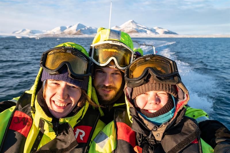 Tre personer tar selfie på RIB-båt i solskinn.