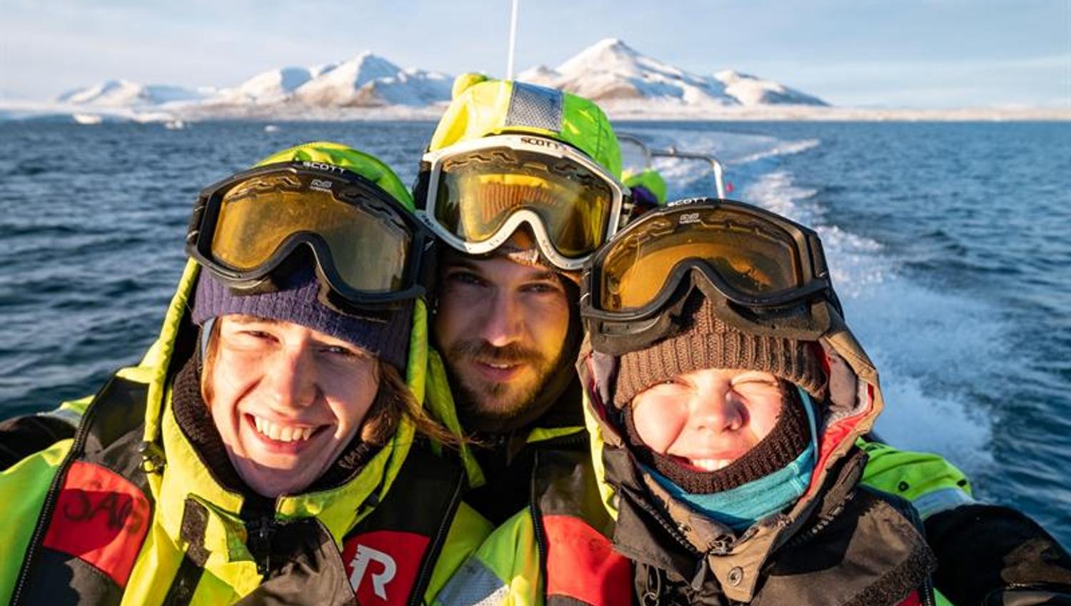 Tre personer tar selfie på RIB-båt i solskinn.