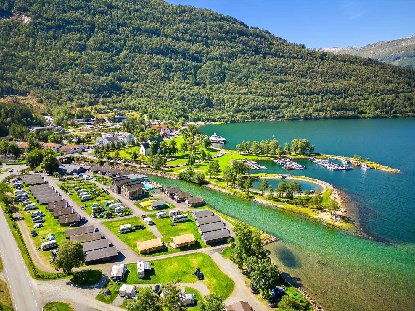 Luftfoto av Mikkelparken Ferietun, med campingområde, hytter og fantastisk utsikt over fjorden og fjella.