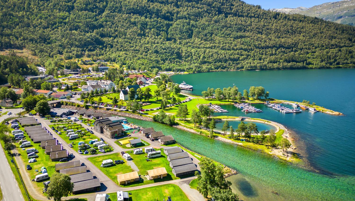 Luftfoto av Mikkelparken Ferietun, med campingområde, hytter og fantastisk utsikt over fjorden og fjella.