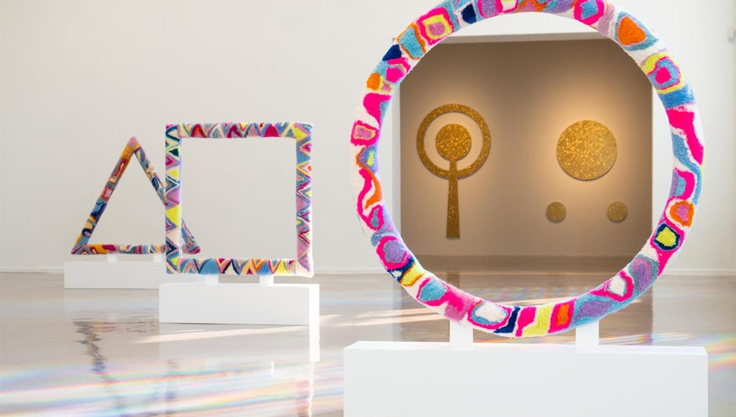 Fargerik kunstinstallasjon med geometriske former i galleri.