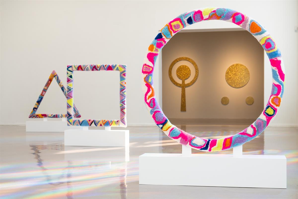 Fargerik kunstinstallasjon med geometriske former i galleri.