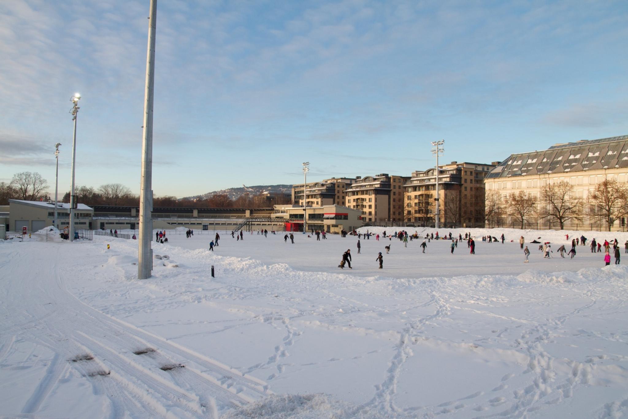 Snow-covered ice rink with people skating.