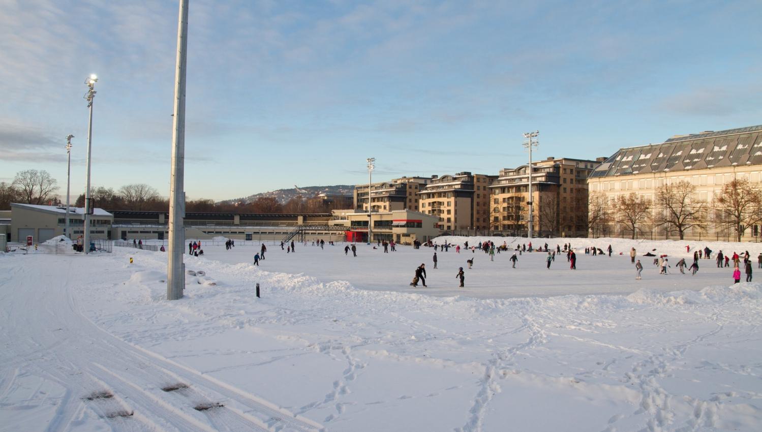 Snow-covered ice rink with people skating.