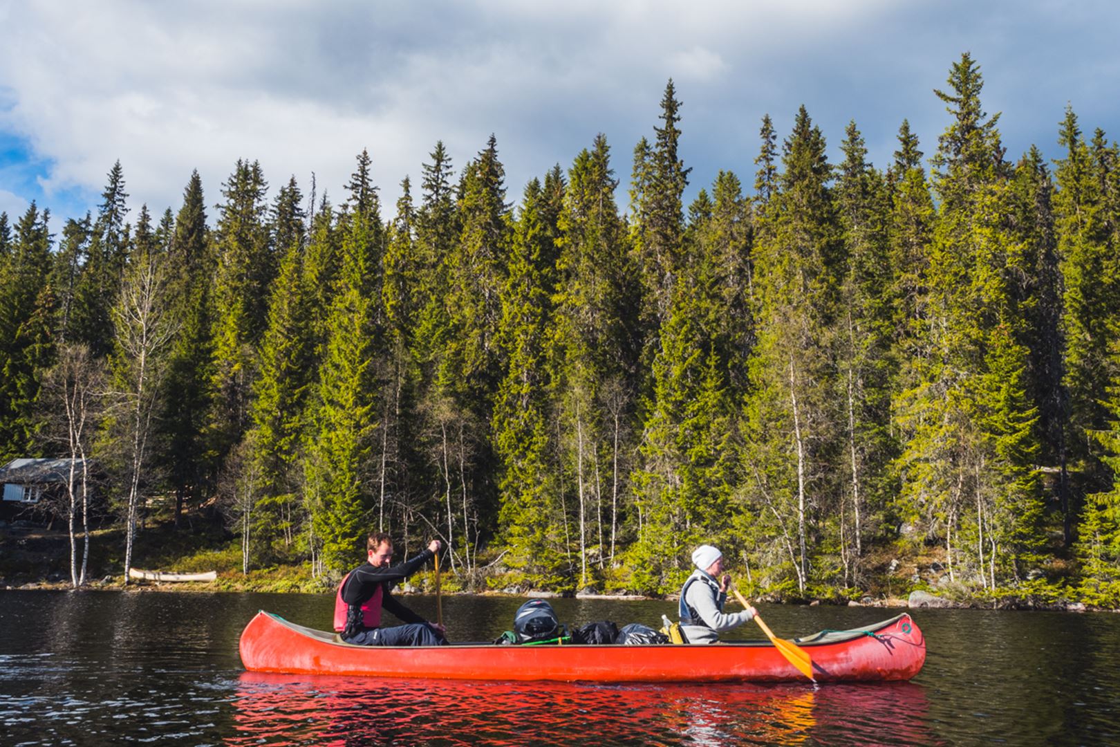 Two people paddling in a red canoe.