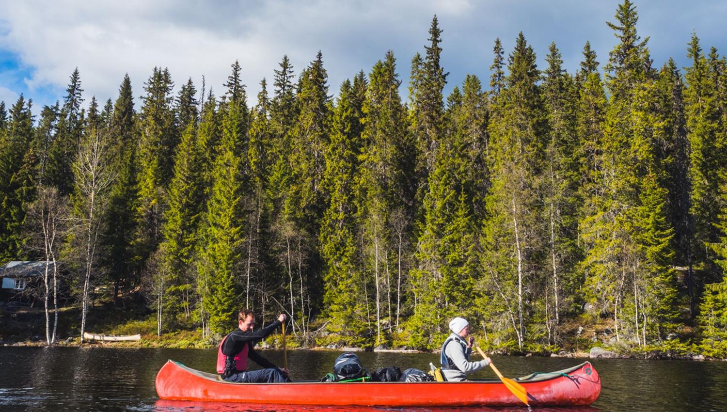 Two people paddling in a red canoe.