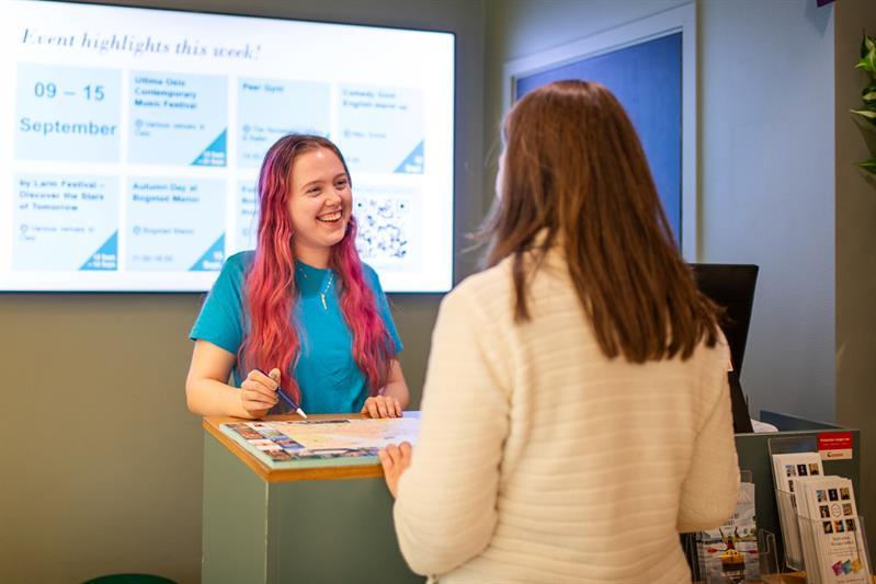 Smiling employee in the tourist information helping a customer