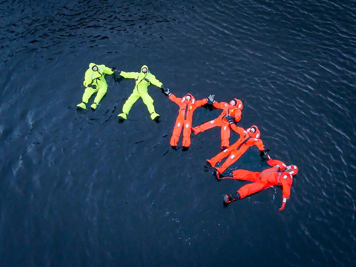 Folk flyter i Hardangerfjorden i overlevingsdraktas