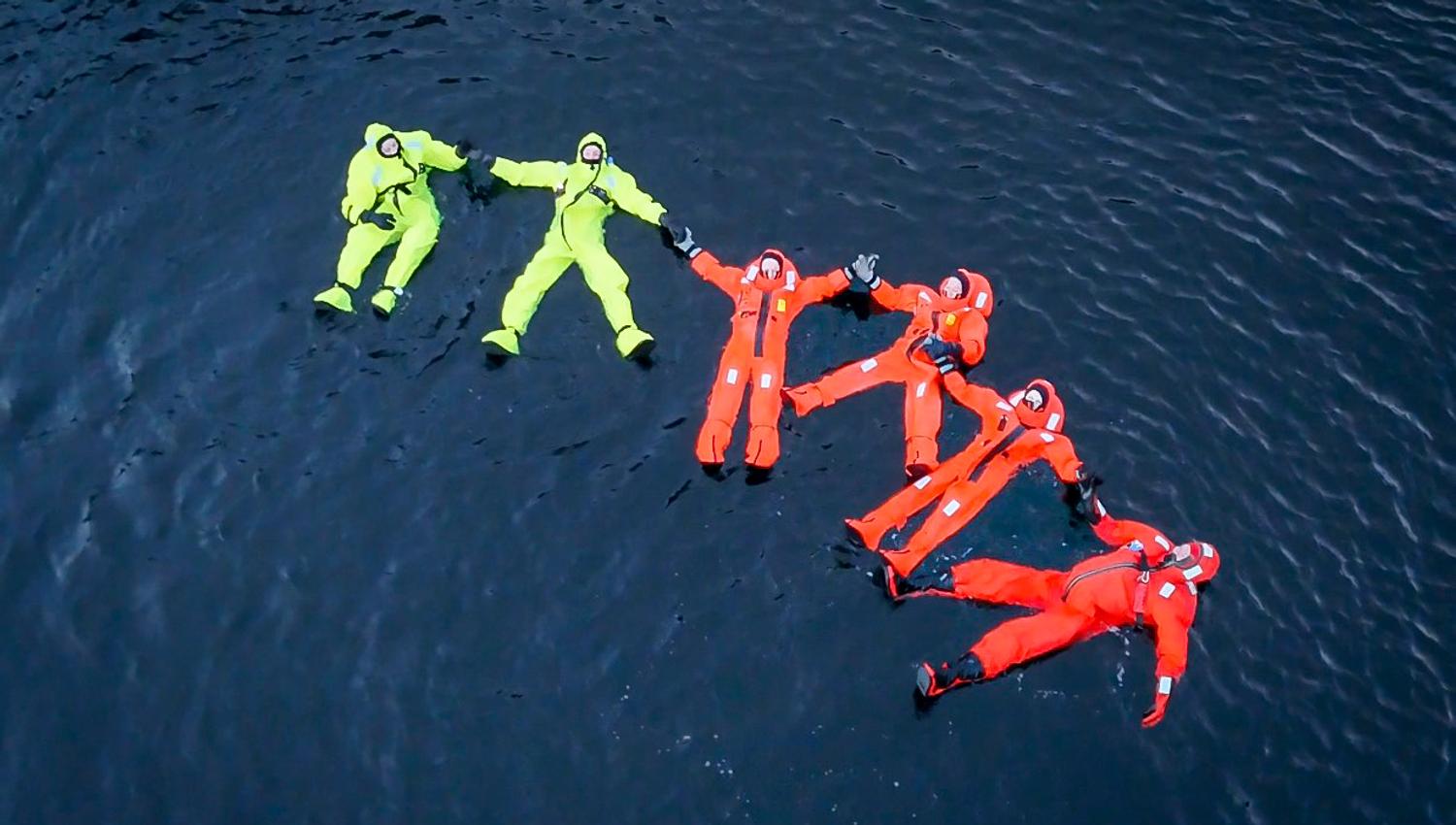 Folk flyter i Hardangerfjorden i overlevingsdraktas
