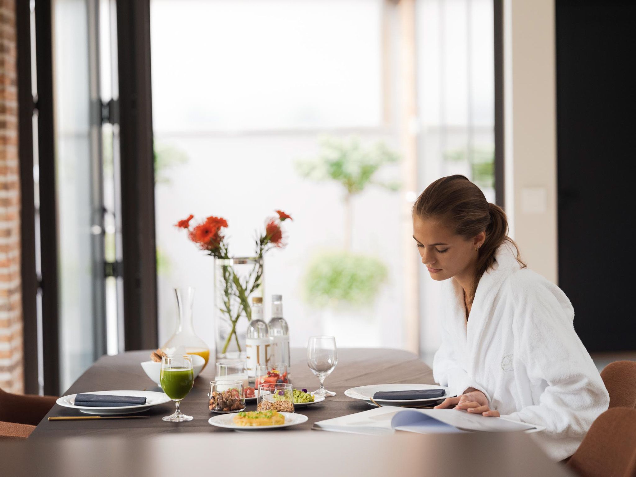 Lady eating breakfast and reading a magazine in a white robe