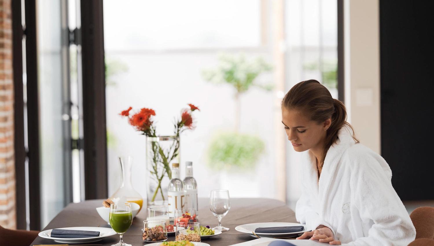 Lady eating breakfast and reading a magazine in a white robe