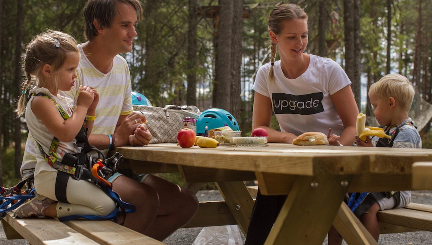 family sitting and eating at the climbing park Høyt og Lavt in Bø in Telemark