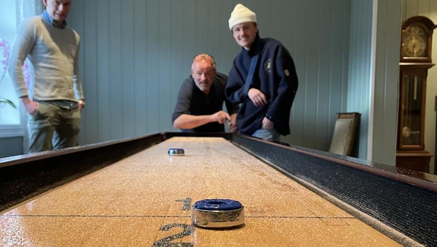 Menn spiller shuffleboard