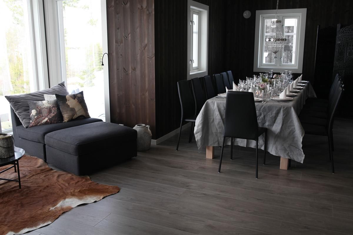 En stue med spisebord og sofa i et rom med mørke trepaneler.