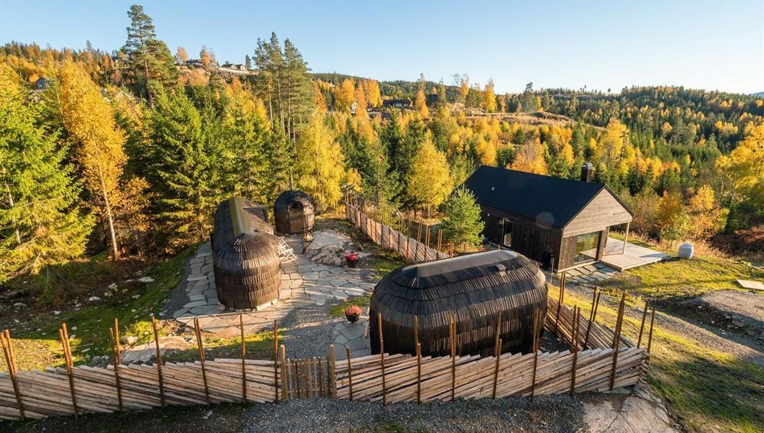 Cabin area with wooden pod cabins surrounded by autumn-colored trees.