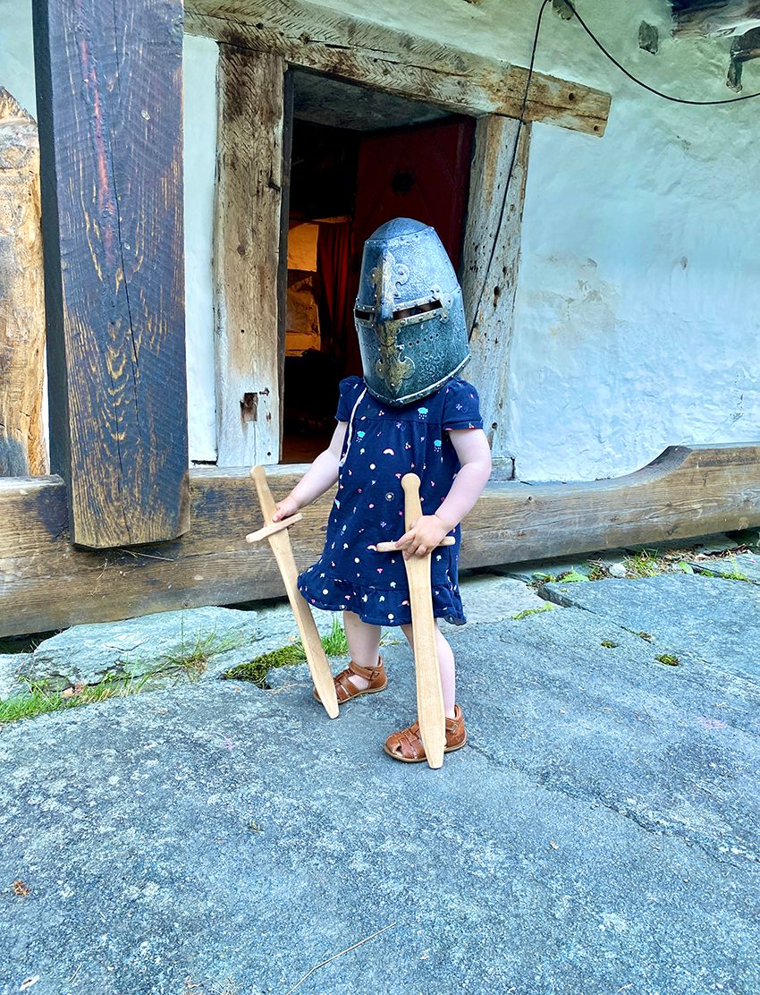 Ein unge med middelalderhjelm og tresverd har stilt seg opp for bilete.