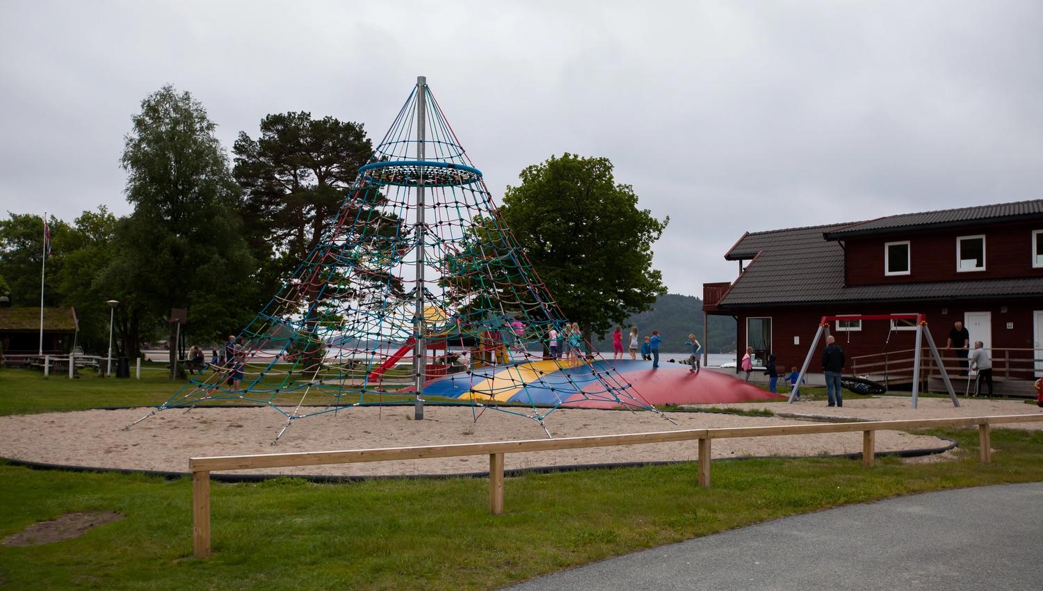 Solstrand Camping playground. A climbing tower in the center and a colorful jumping pillow beside it.
