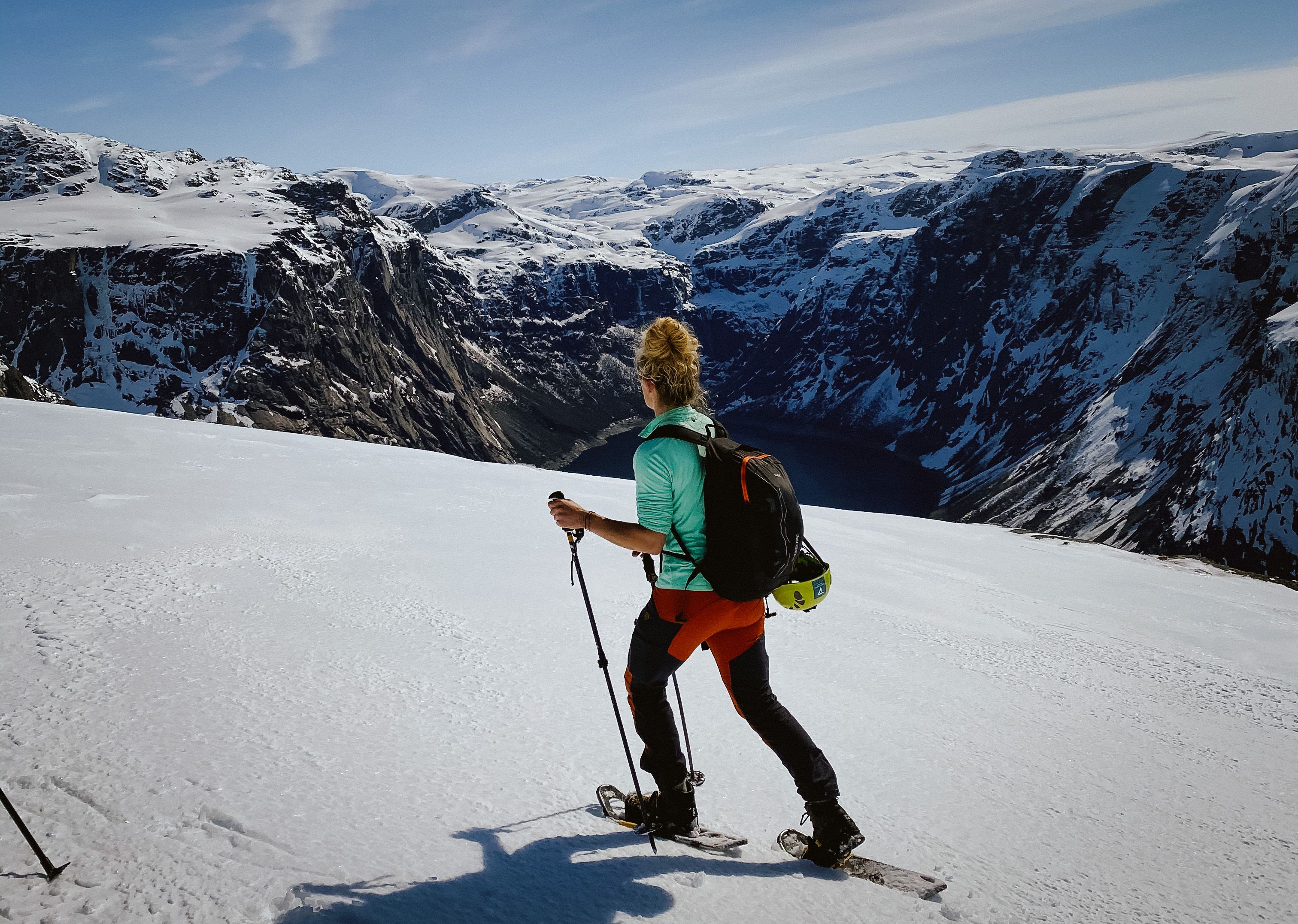 Snowshoe hiker on a snowy mountain plateau overlooking the fjord near Trolltunga.