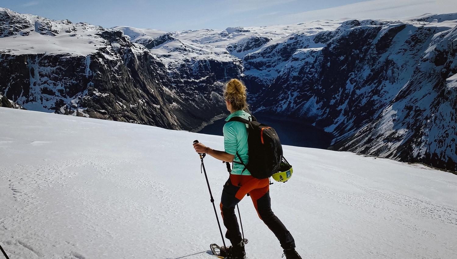 Snowshoe hiker on a snowy mountain plateau overlooking the fjord near Trolltunga.