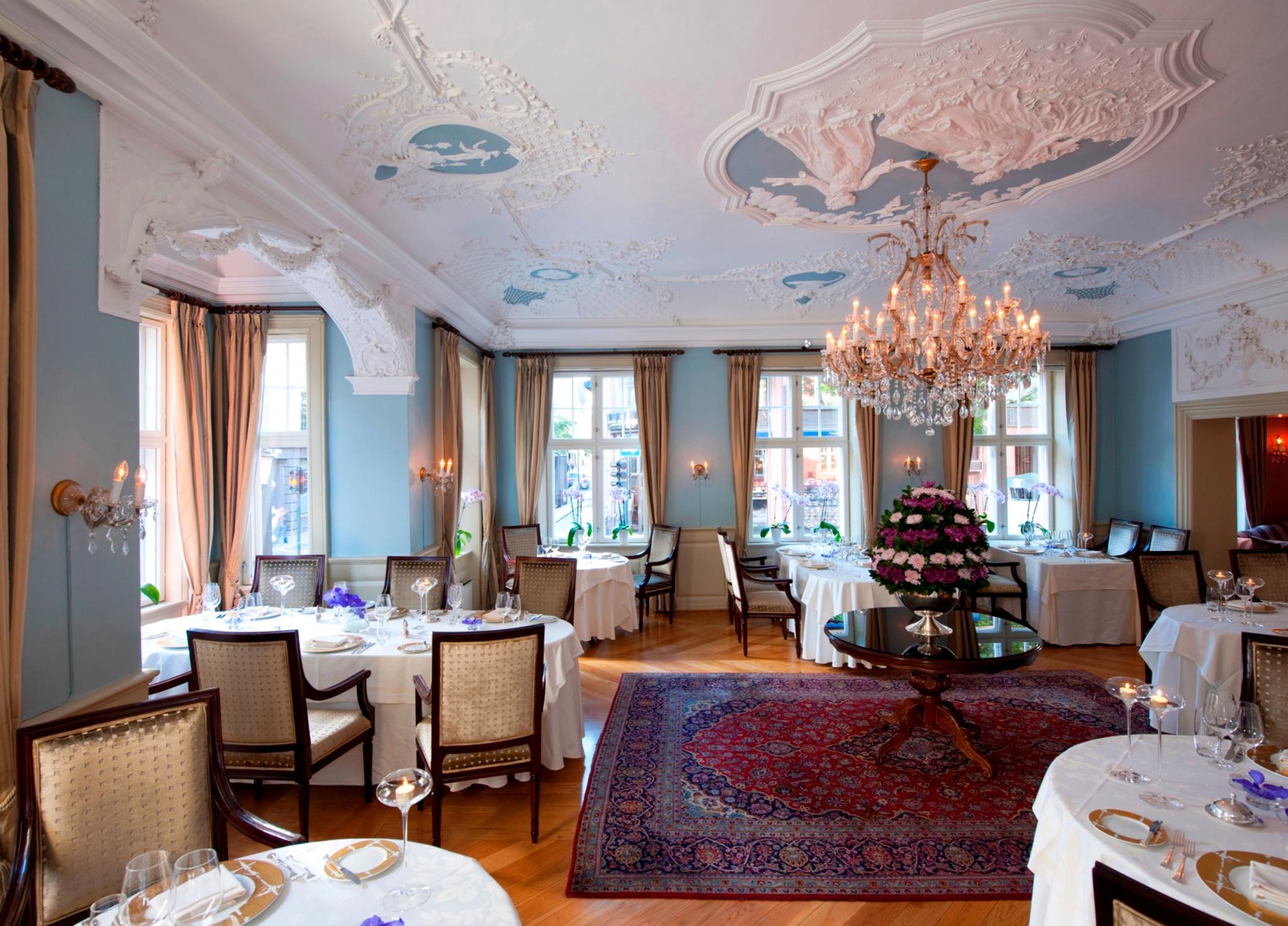 Set tables in hall with blue walls. eye crown and stucco in the ceiling.