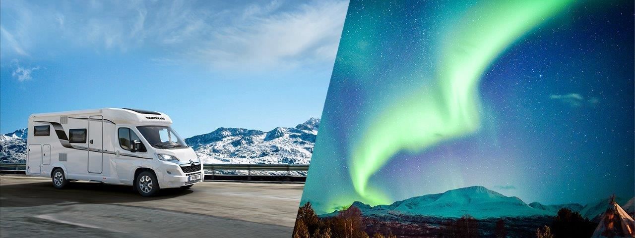 Motorhome in front of snow-covered mountains and Northern Lights over mountain landscape at night.