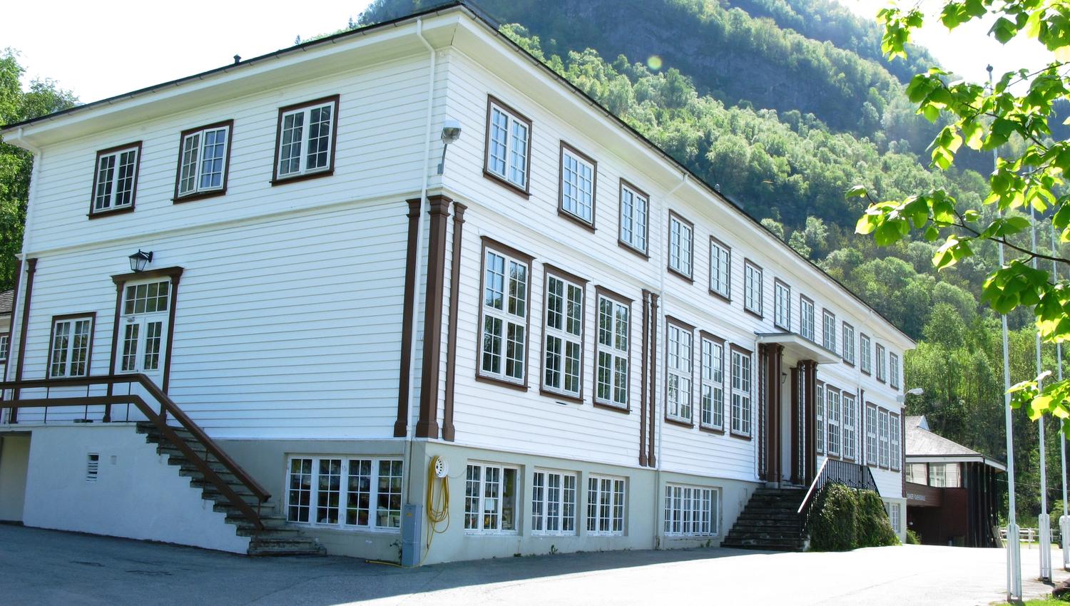 Hardanger Hostel B&B tett på – stort trehus med tradisjonell stil og grøne fjell i bakgrunnen.